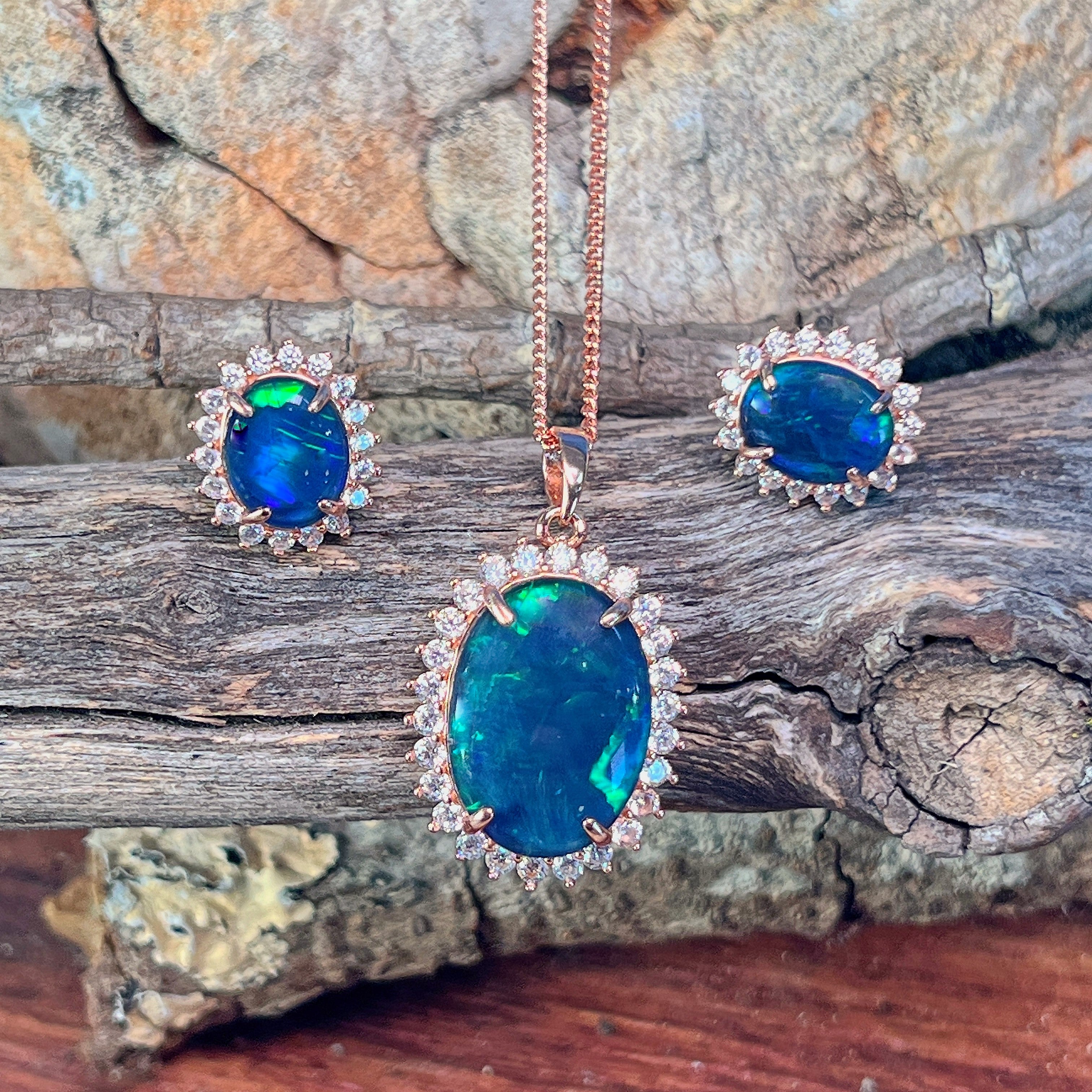 Rose gold-plated opal triplet halo pendant and matching studs on weathered driftwood