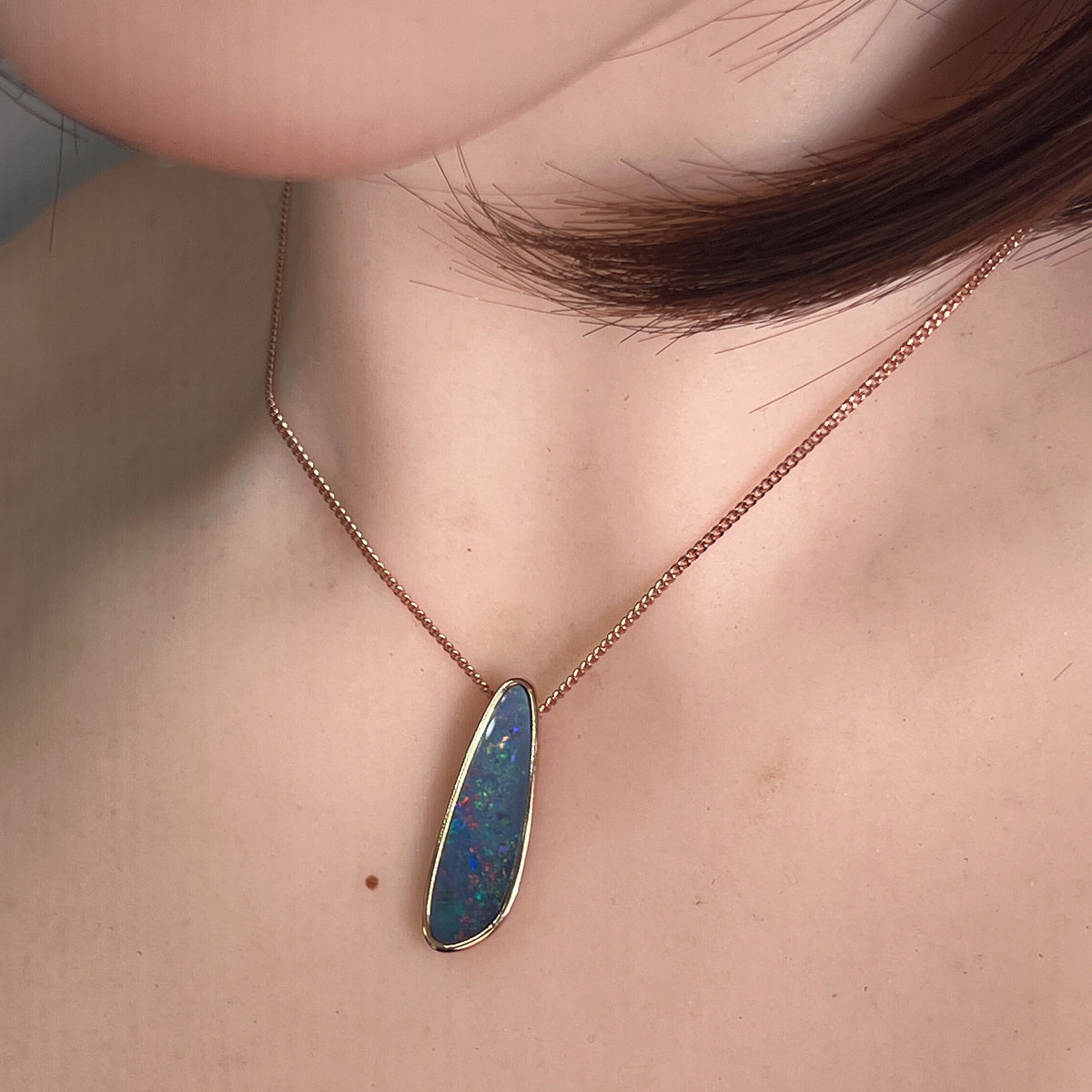 Worn Australian opal doublet pendant in rose gold-plated silver, red, blue, yellow and green, 27 x 8mm
