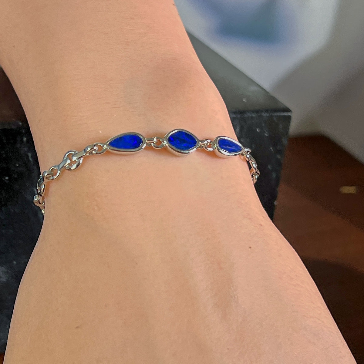 Sterling silver bracelet with three opal doublets worn on the wrist, showing the length of the chain