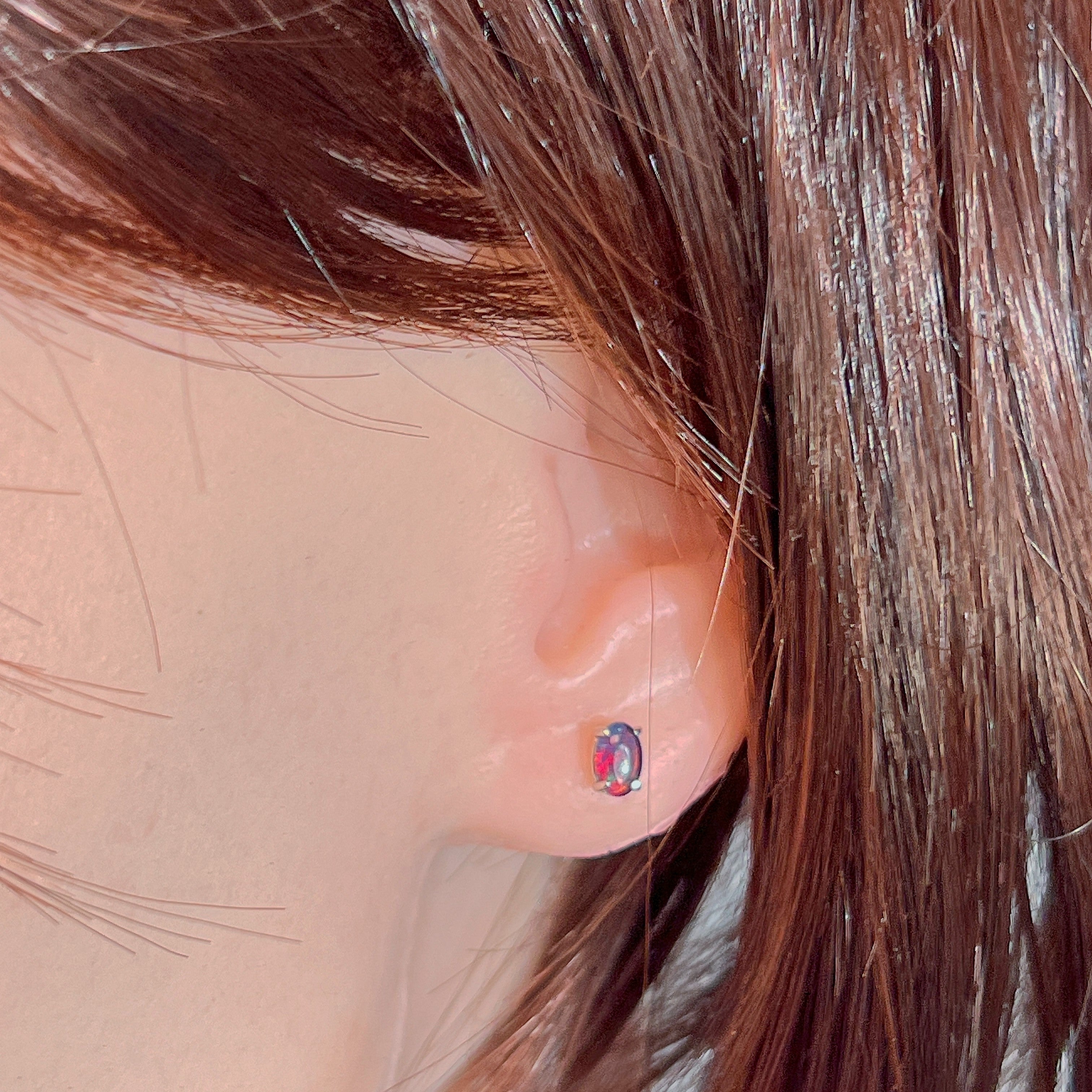 Claw-set opal triplet stud earring worn on the ear, showing its scale on the earlobe