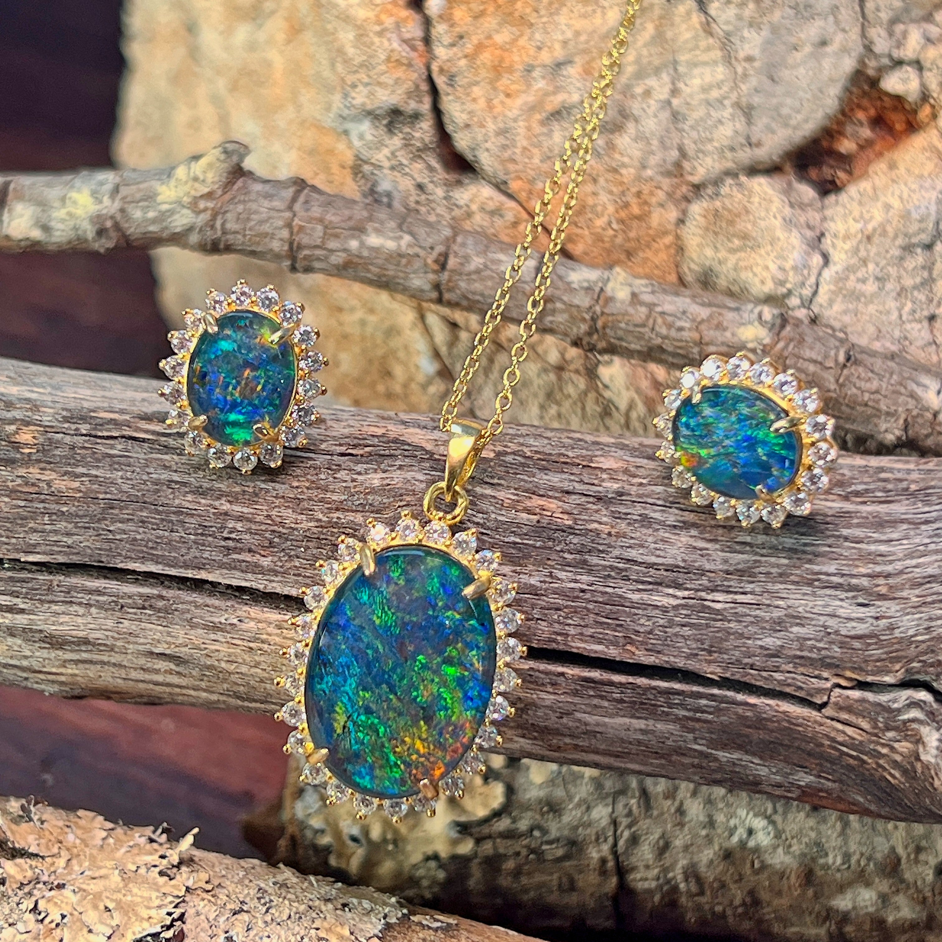Opal triplet halo pendant and cluster earrings in gold-plated silver against driftwood