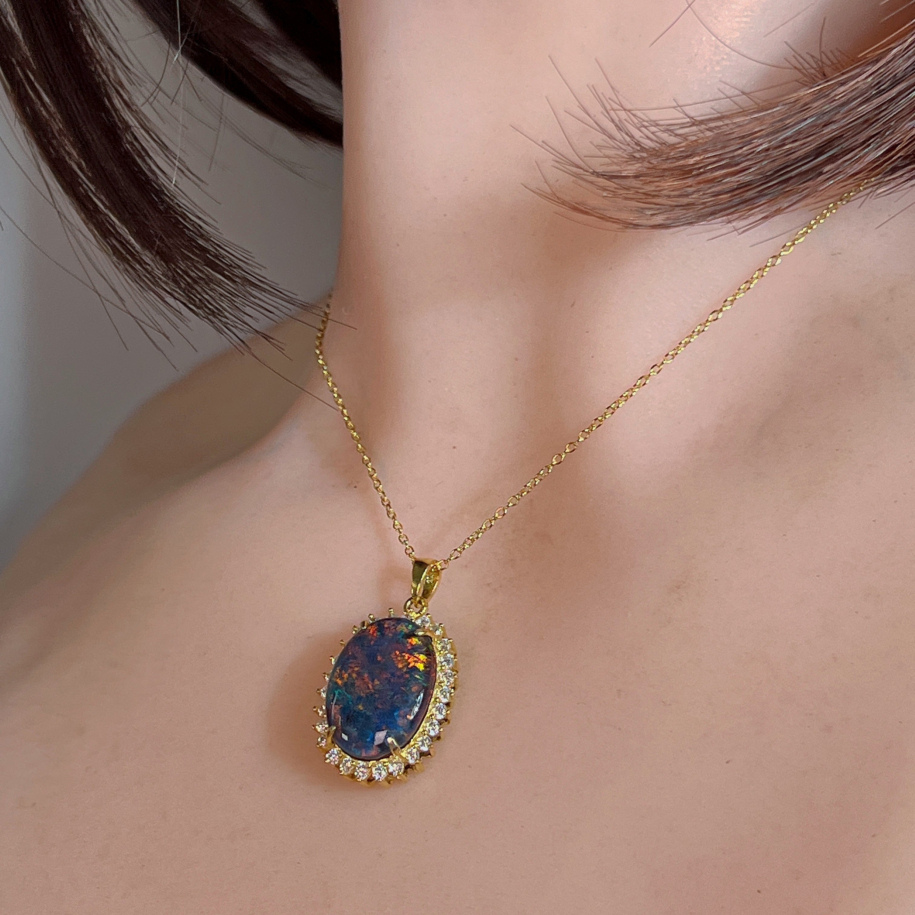 Yellow gold-plated opal triplet halo pendant worn at the neckline, close view
