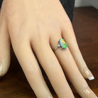 Oval Australian black opal ring worn on the hand, 18kt white gold with two small diamonds