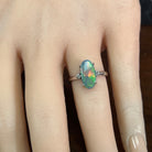 Hand wearing an 18kt white gold black opal and diamond ring, 1.4ct oval Australian black opal