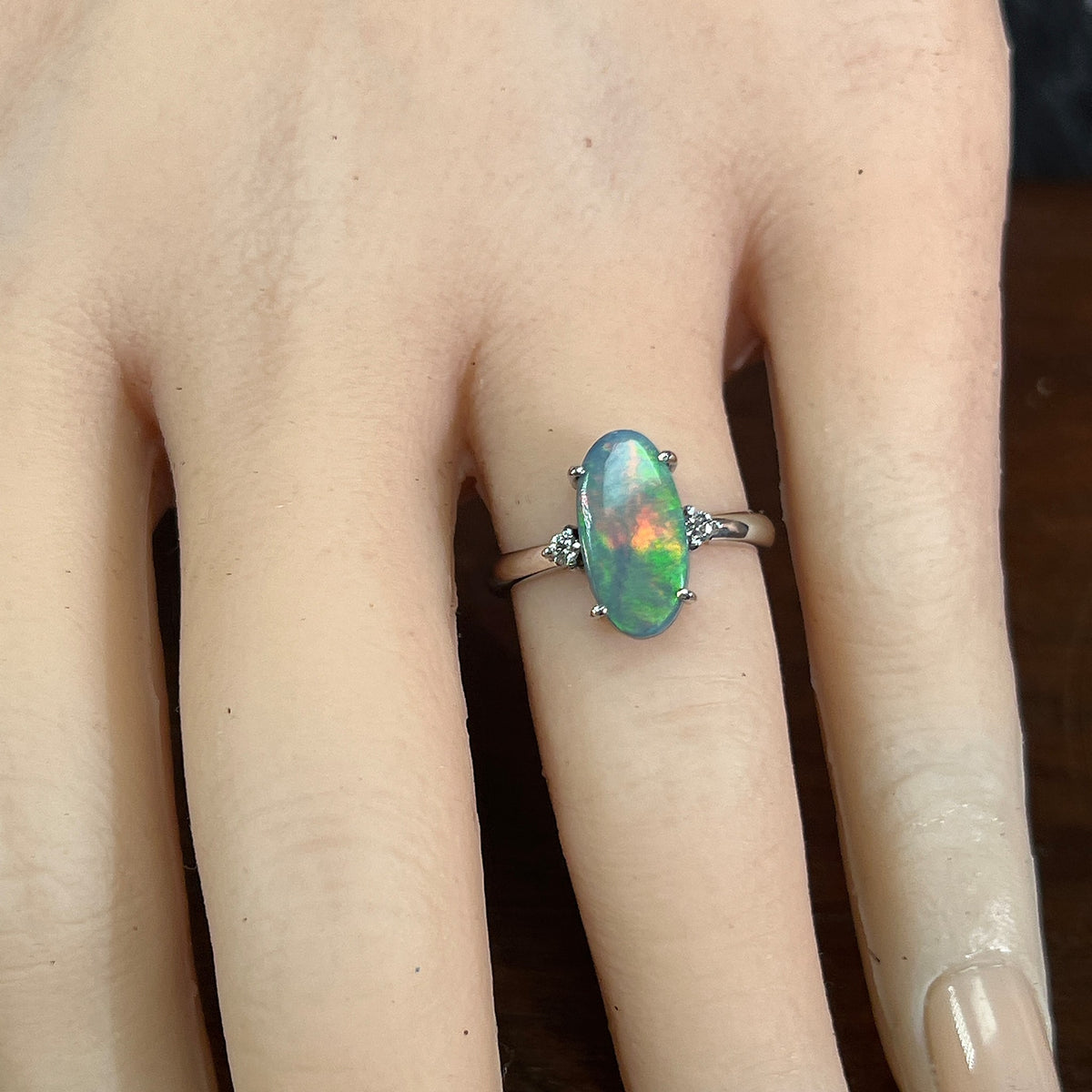 Hand wearing an 18kt white gold black opal and diamond ring, 1.4ct oval Australian black opal