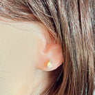 Oval crystal opal and diamond stud earring worn in the ear