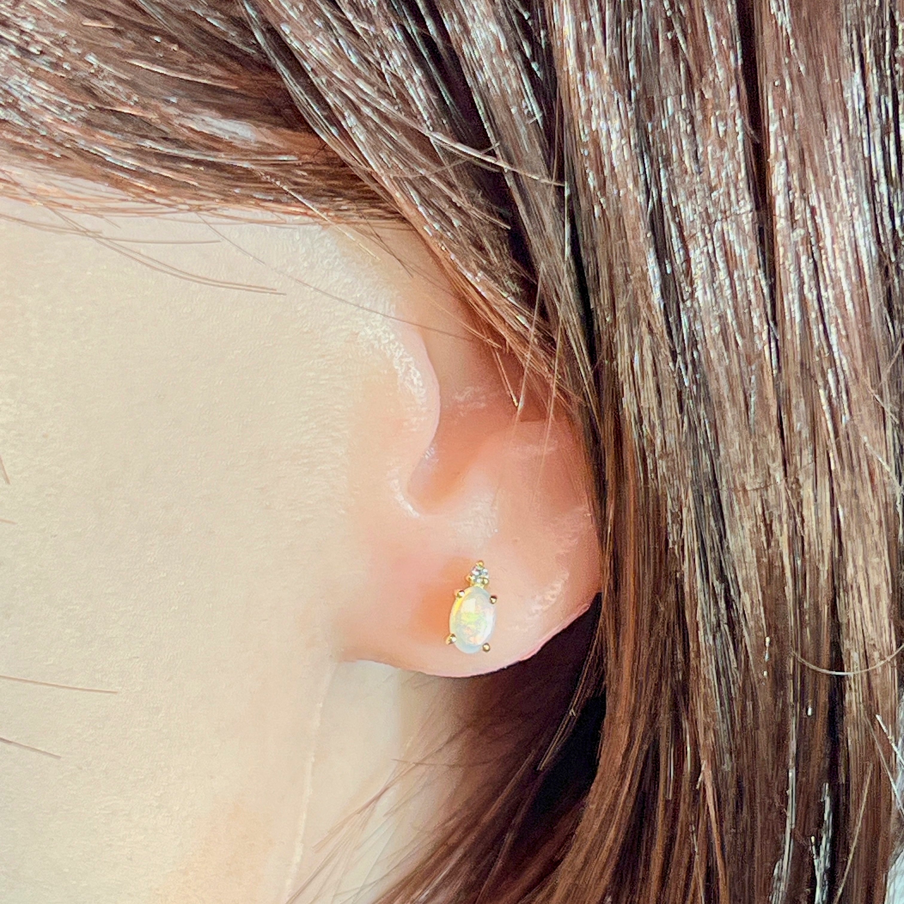 Oval crystal opal and diamond stud earring worn in the ear