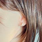 Worn view of the 6x4mm oval crystal opal stud with its diamond accent
