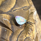 Australian boulder opal tilted to show its cabochon dome, green and pink play of colour