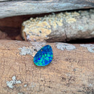 Loose 3.53ct drop shaped Australian opal doublet resting on weathered driftwood