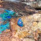 Blue green play-of-colour in a freeform 0.79ct Australian opal doublet resting on rock