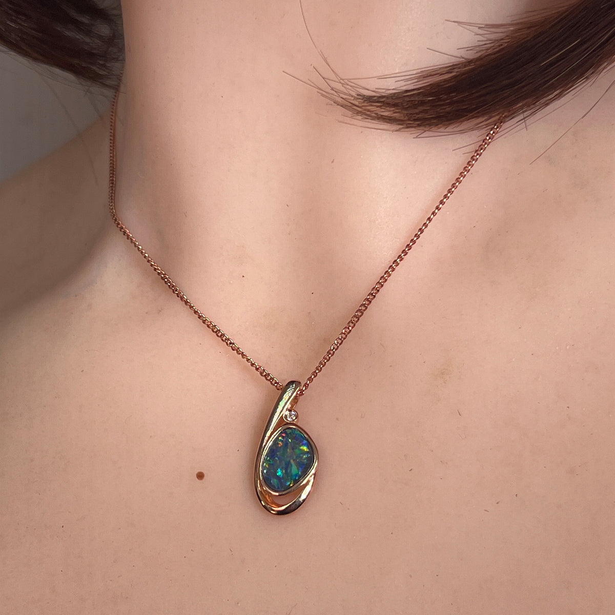 11 x 8mm freeform Australian opal doublet pendant worn at the neck, rose gold-plated silver