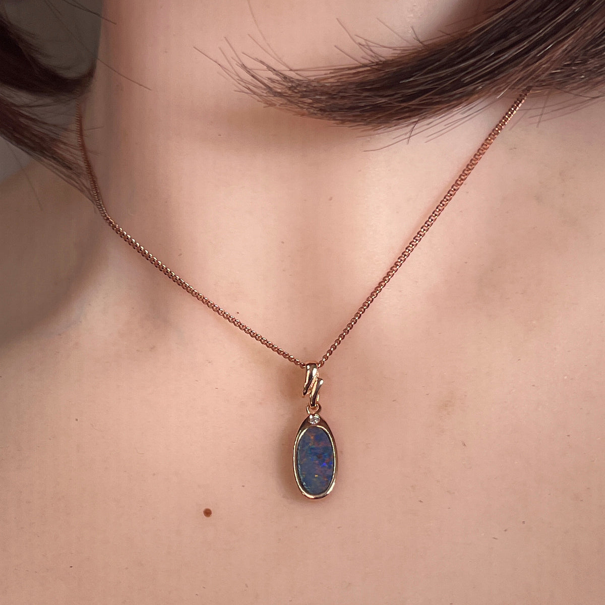 Australian opal doublet pendant worn at the neck, red and blue play-of-colour