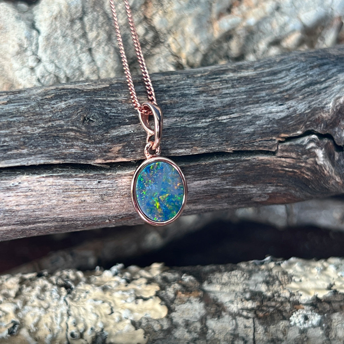 green, red, blue and yellow play-of-colour in a 10 x 8mm oval Australian opal doublet pendant
