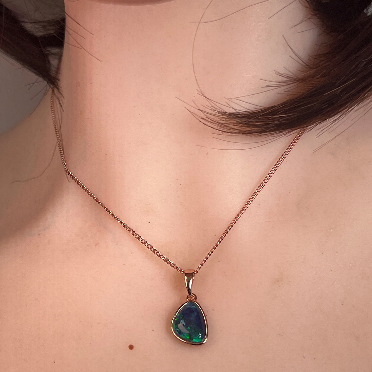 Australian opal triplet pendant worn at the neck, red, green and blue play-of-colour