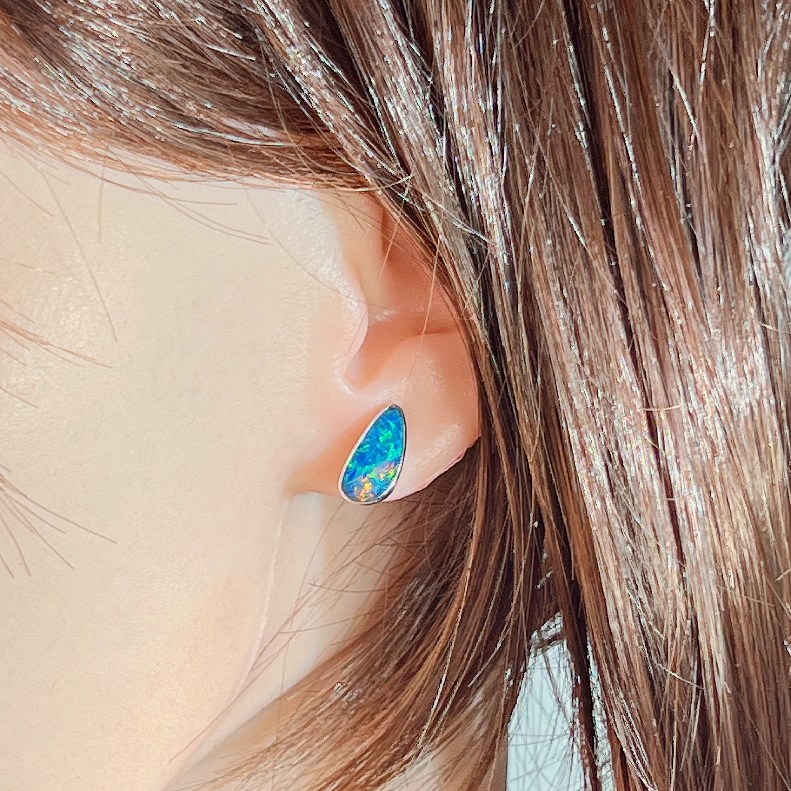 Opal doublet stud earring in silver worn on the ear, close view of the play-of-colour