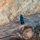 Bezel-set freeform opal doublet in silver, close view against driftwood and sandstone