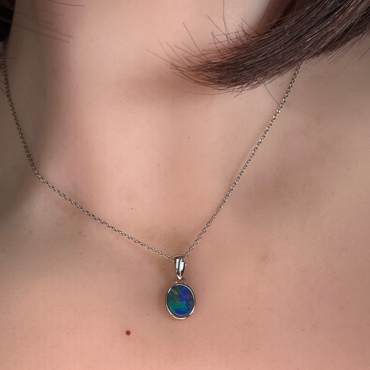 9.5 x 7mm oval Australian opal doublet pendant worn at the neck, sterling silver