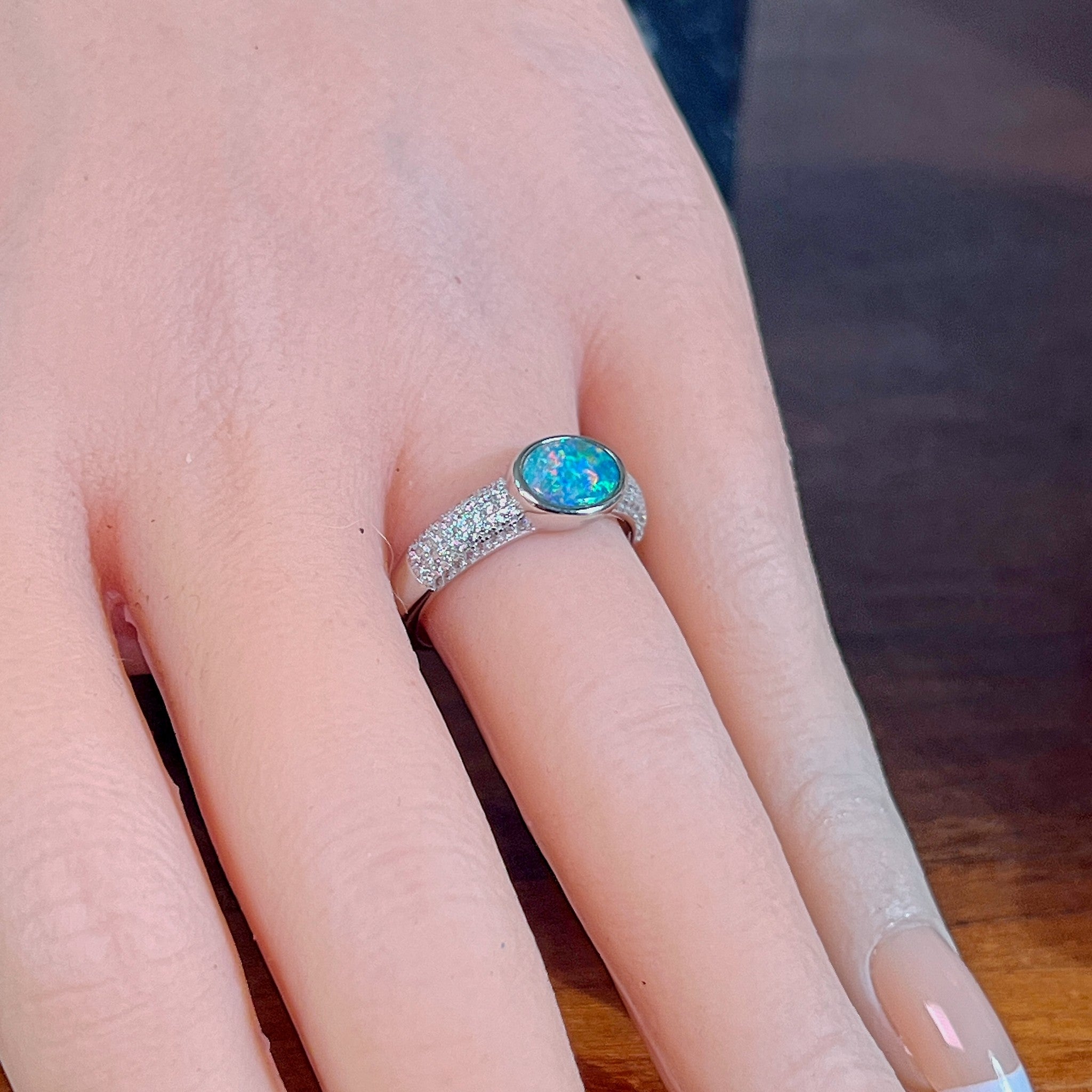Oval opal doublet ring on a pave silver band worn on the hand, showing its scale on the finger