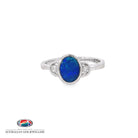 Oval opal doublet ring in sterling silver, bezel set with a cubic zirconia to each side, in blue and green
