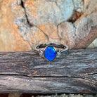 Blue opal doublet ring in silver resting on weathered driftwood