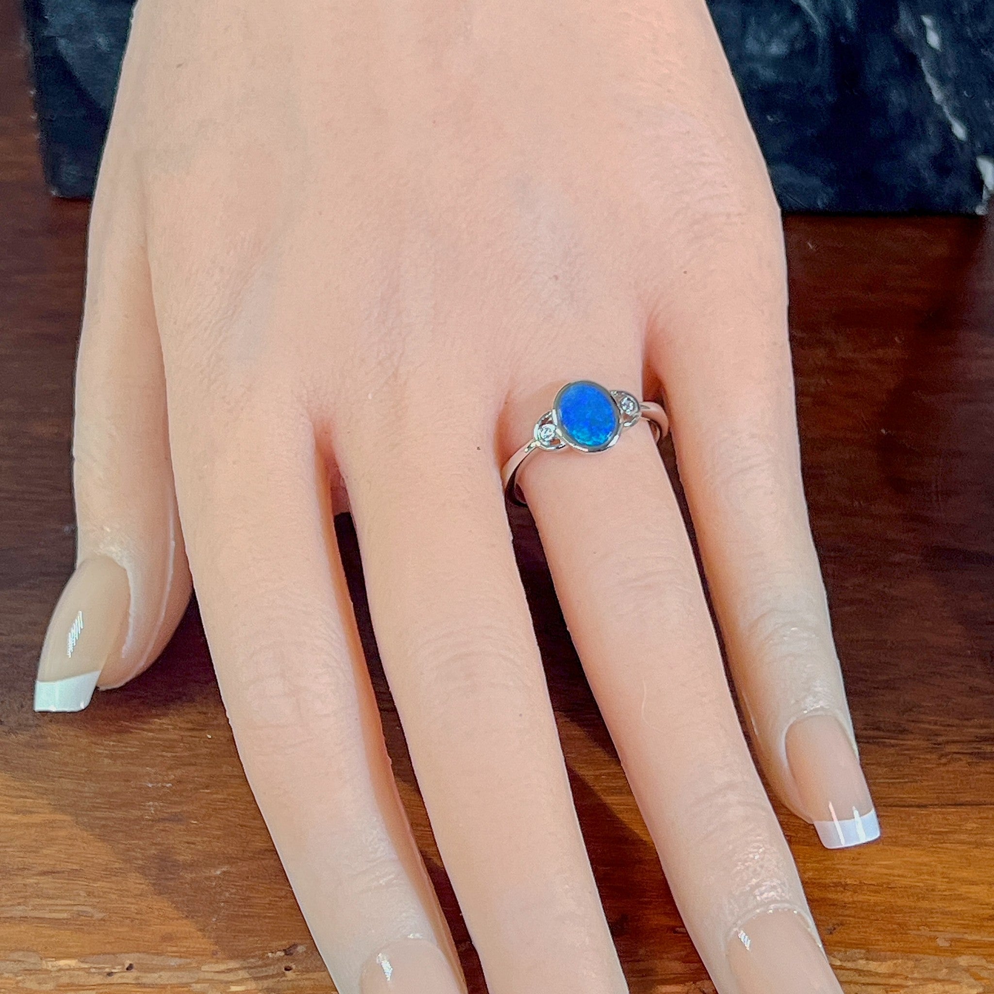 Blue opal doublet ring in silver worn on the hand, full view across the fingers