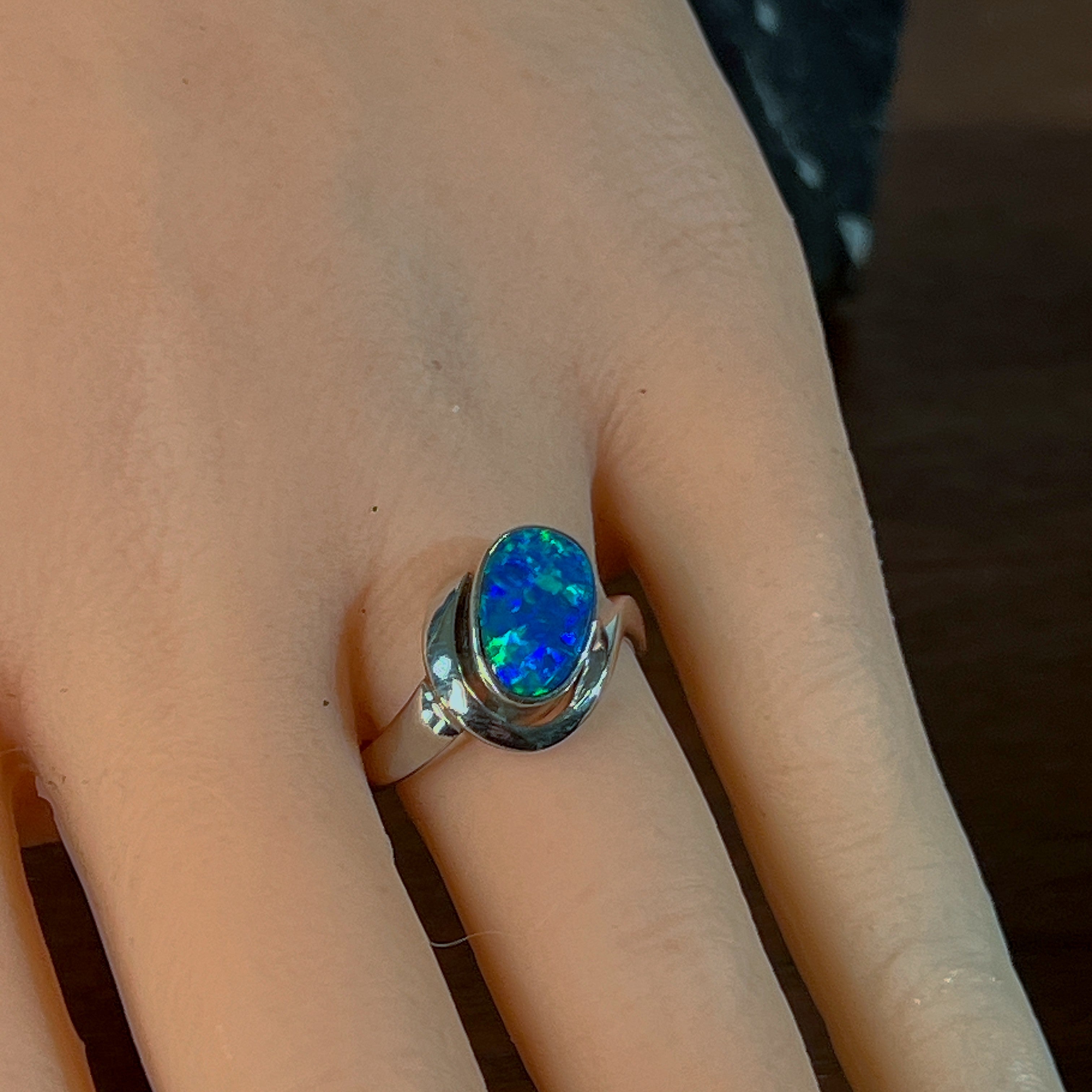 Oval opal doublet solitaire ring worn on the hand, showing its scale on the finger