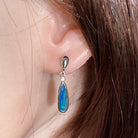 15 x 5mm pear-shaped Australian opal doublet earrings worn on the ear, sterling silver