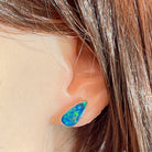 Pear-shaped opal doublet stud earring worn on the ear, showing its scale on the earlobe