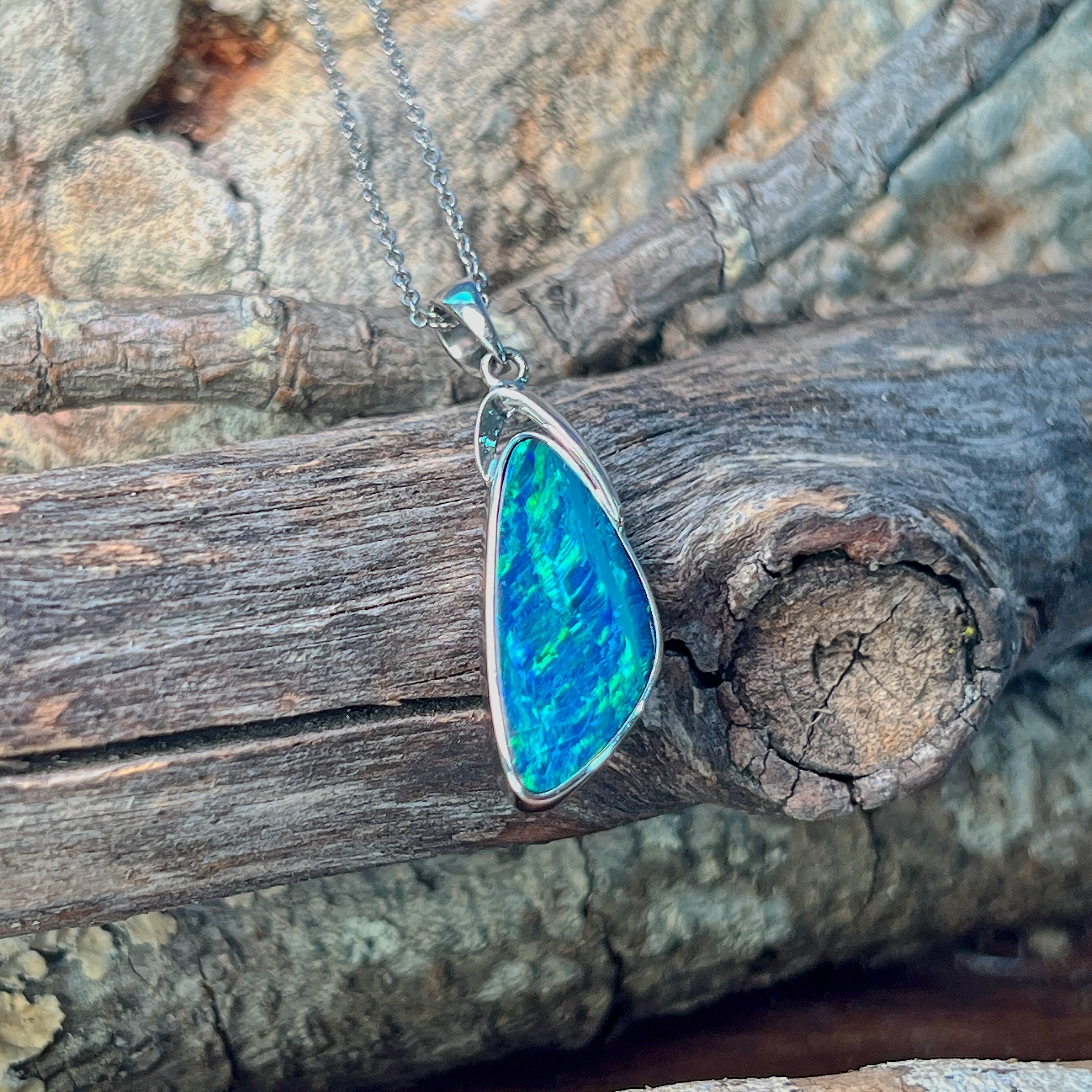 Wing-shaped opal doublet pendant in silver showing vivid blue and green play-of-colour