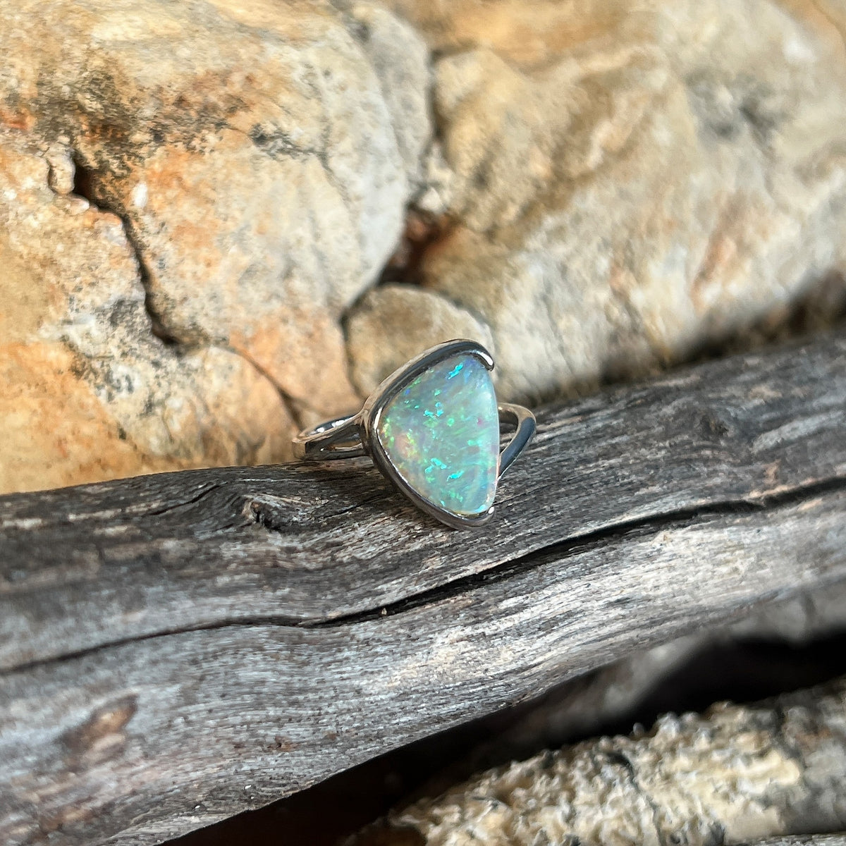 Australian crystal opal ring, triangular 1.8ct solid stone, sterling silver half bezel, green and blue flashes, on timber