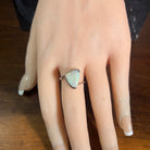 Australian crystal opal 13x10mm ring, sterling silver cross over band, solid opal, green and blue, on a display hand