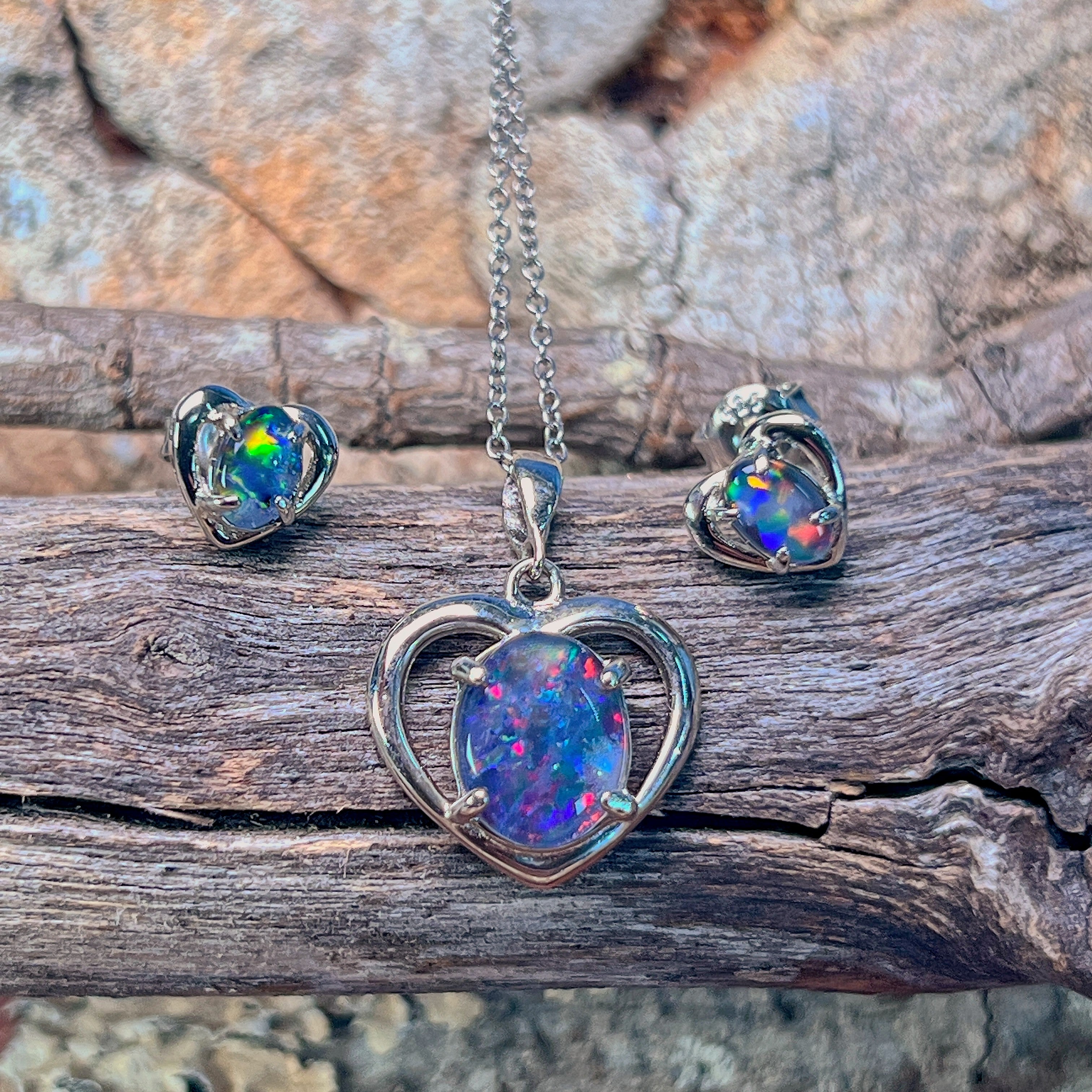 Silver heart opal triplet pendant and matching heart studs on weathered driftwood