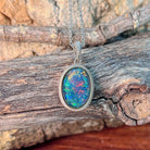 14x10mm oval opal triplet pendant in sterling silver angled on driftwood