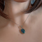 Opal triplet pendant with milgrain bezel worn at the neck, close view