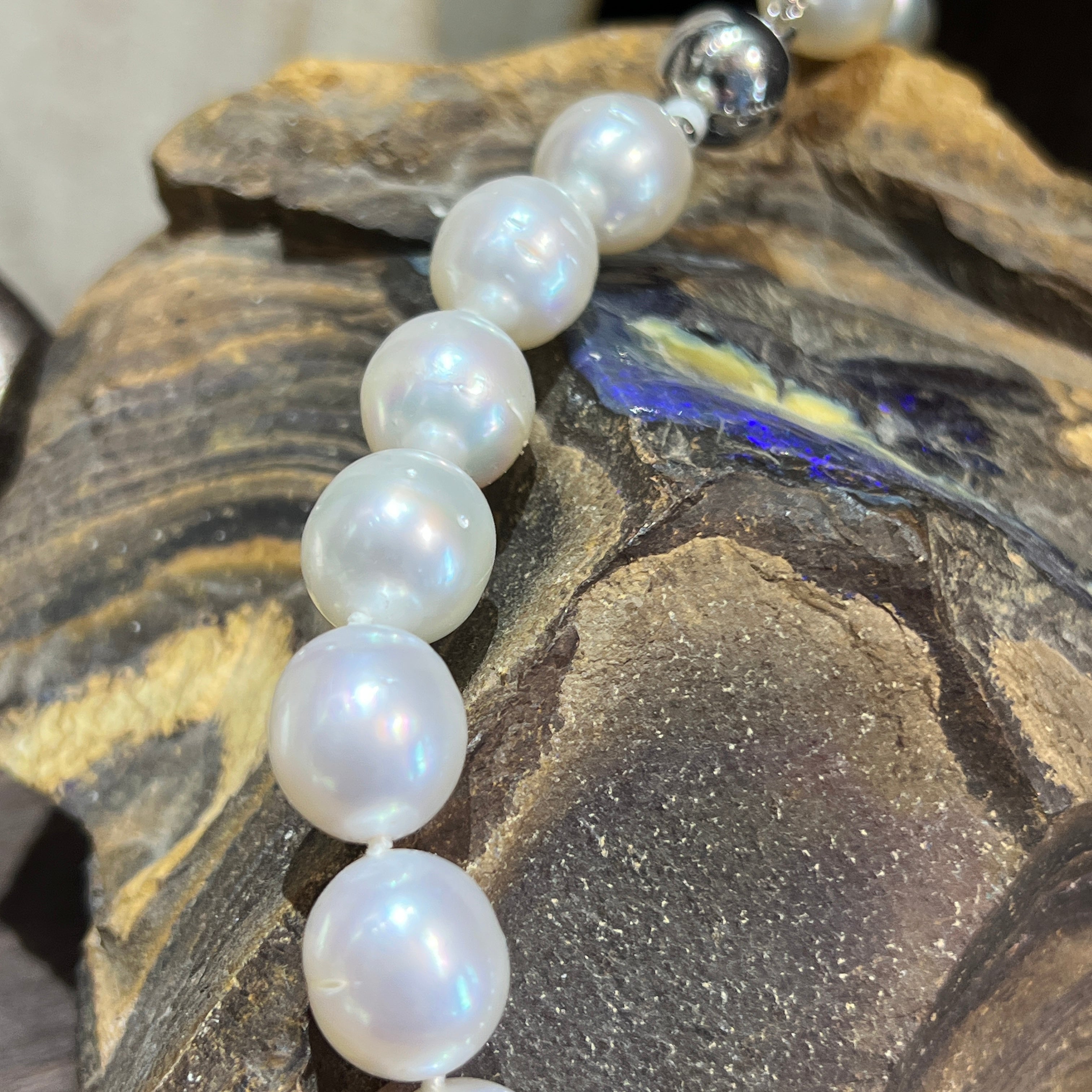 White South Sea pearl necklace draped over opal-bearing ironstone, clasp at the top
