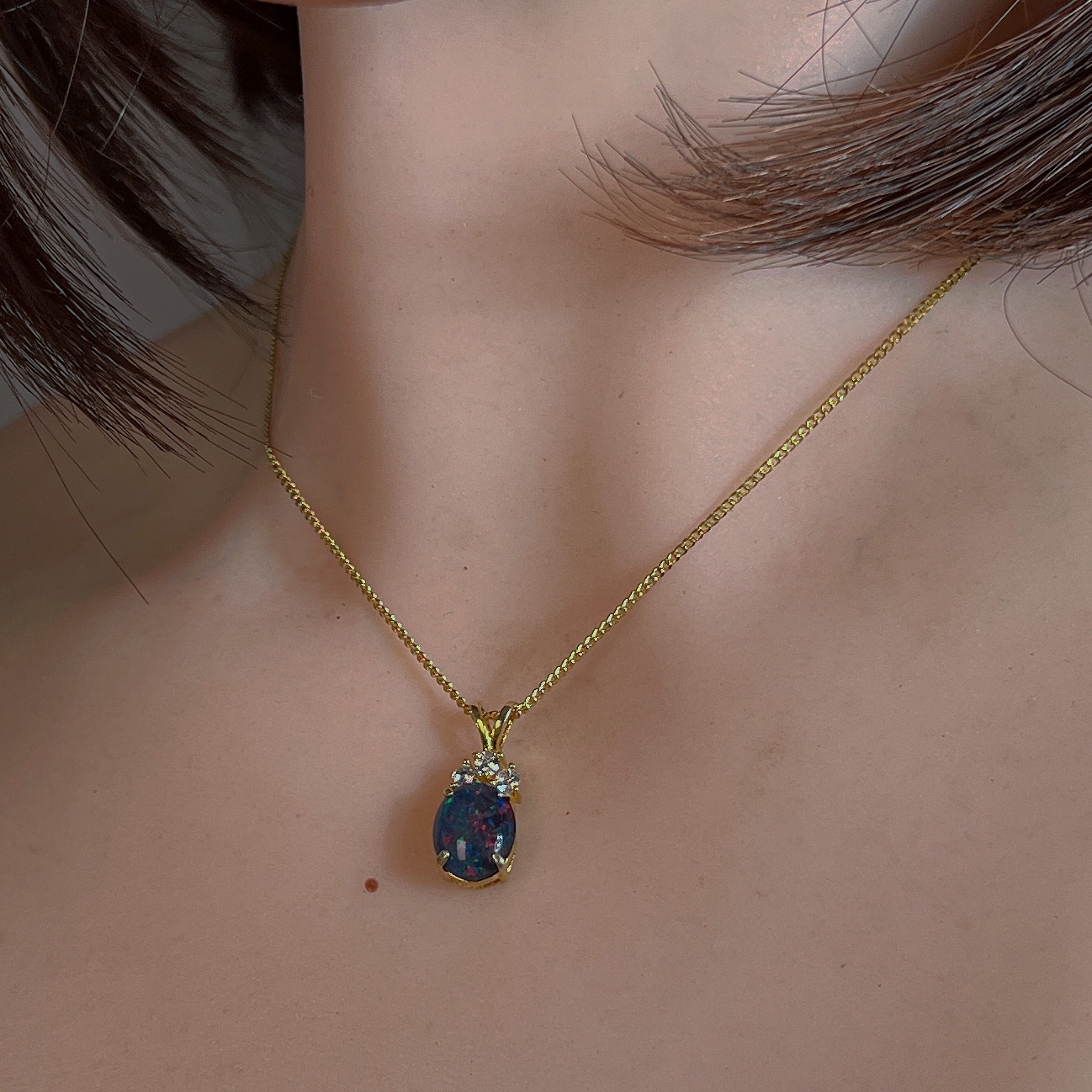 Oval opal triplet pendant worn at the neck, showing its scale on the collarbone