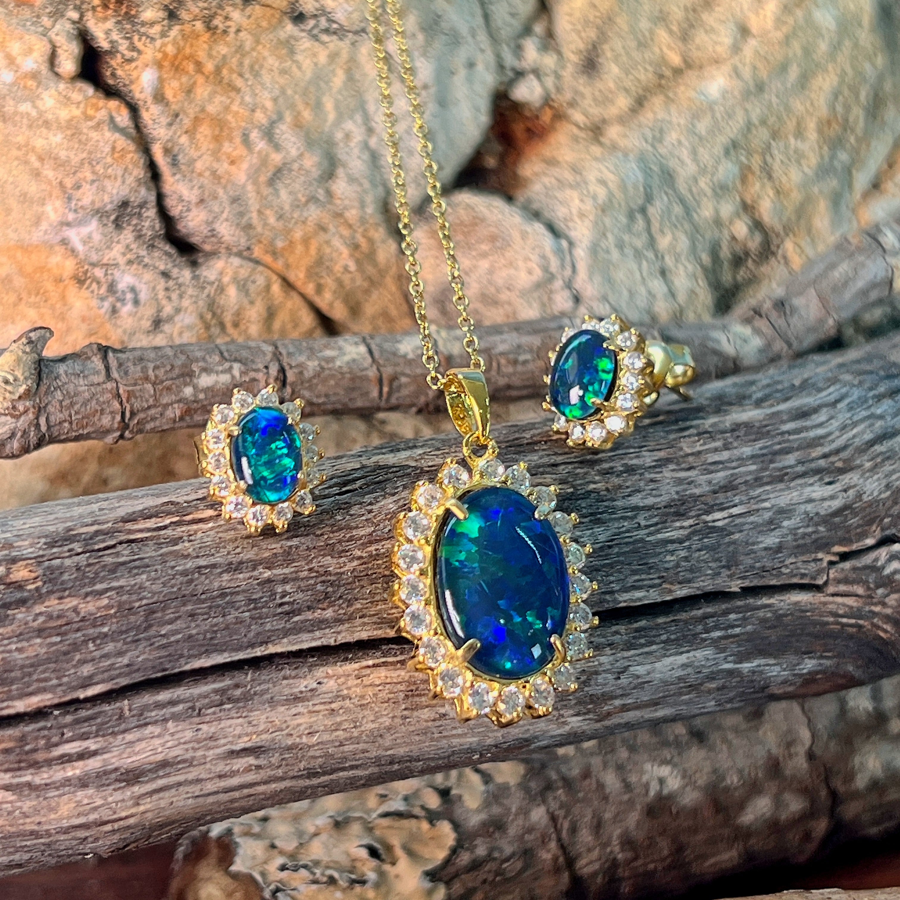 Opal triplet halo pendant and 7x5mm cluster earrings in gold-plated silver against driftwood