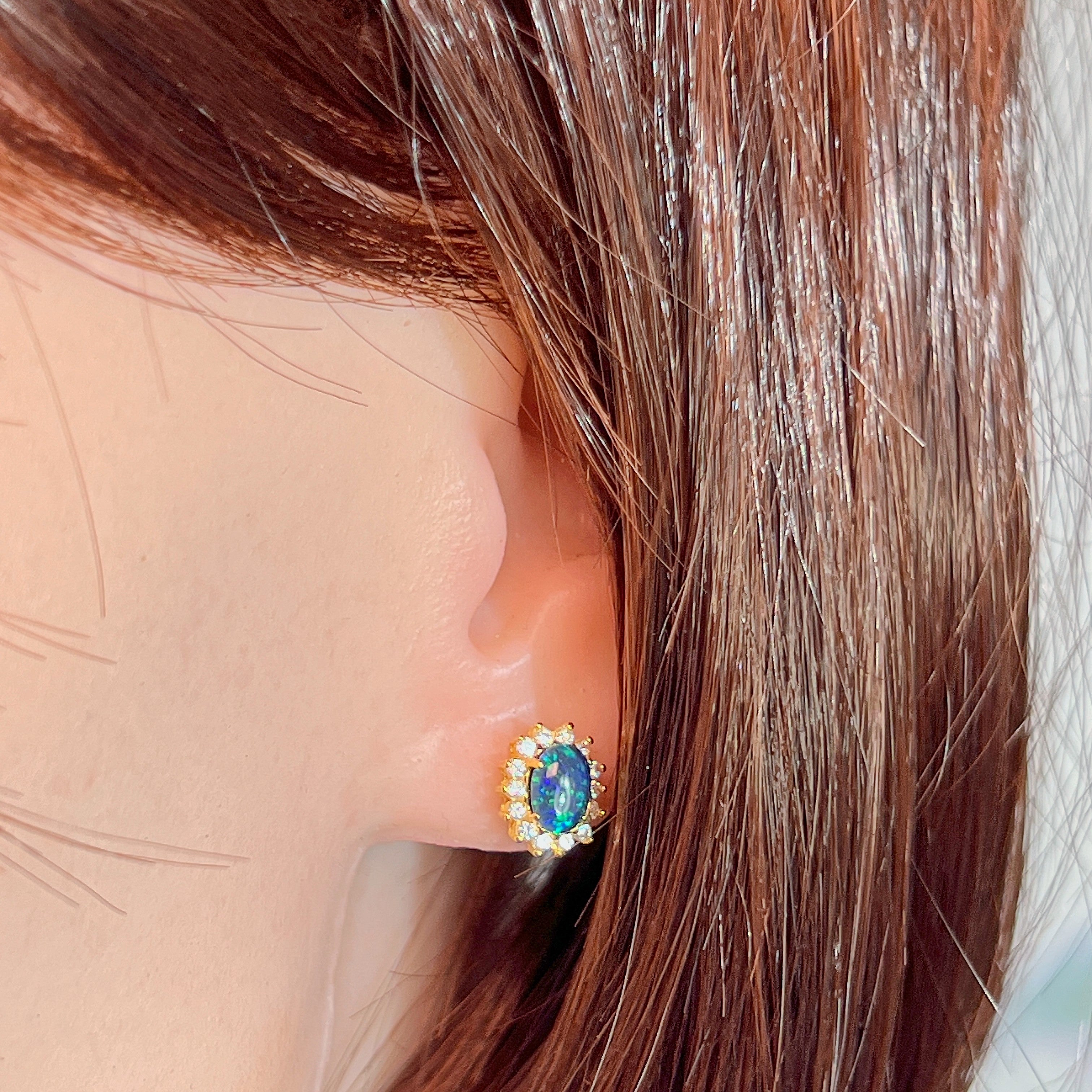 Opal triplet cluster stud earring worn on the ear, showing its scale on the earlobe