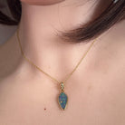 16 x 8mm oval Australian opal doublet pendant worn at the neck, yellow gold-plated silver