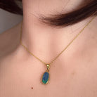 12 x 6mm oval Australian opal doublet pendant worn at the neck, yellow gold-plated silver
