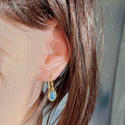 Worn close-up of the 8x6mm oval opal triplet earring in yellow gold plated sterling silver